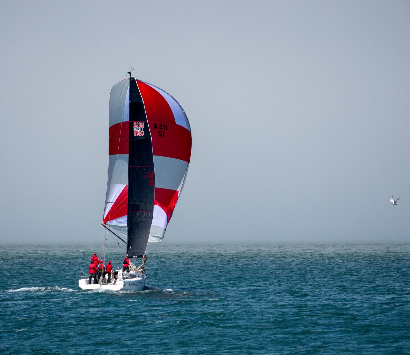 A group actively sailing with a vibrant spinnaker during a race on open water.